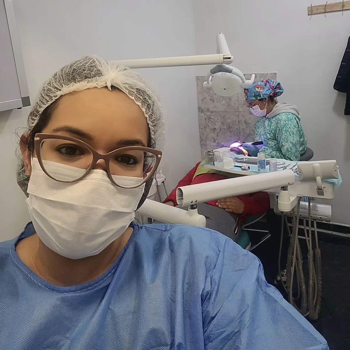 Dentista de Clínica DentalDent en la consulta, con un paciente en atención al fondo